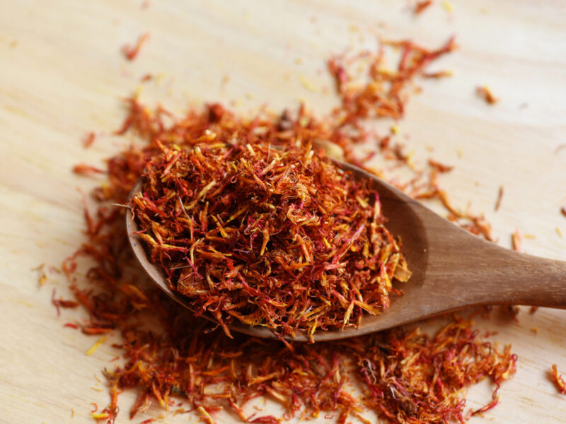 Dried safflower for herbal tea on wood background, dry safflower petals in wooden spoon, Saffron substitute