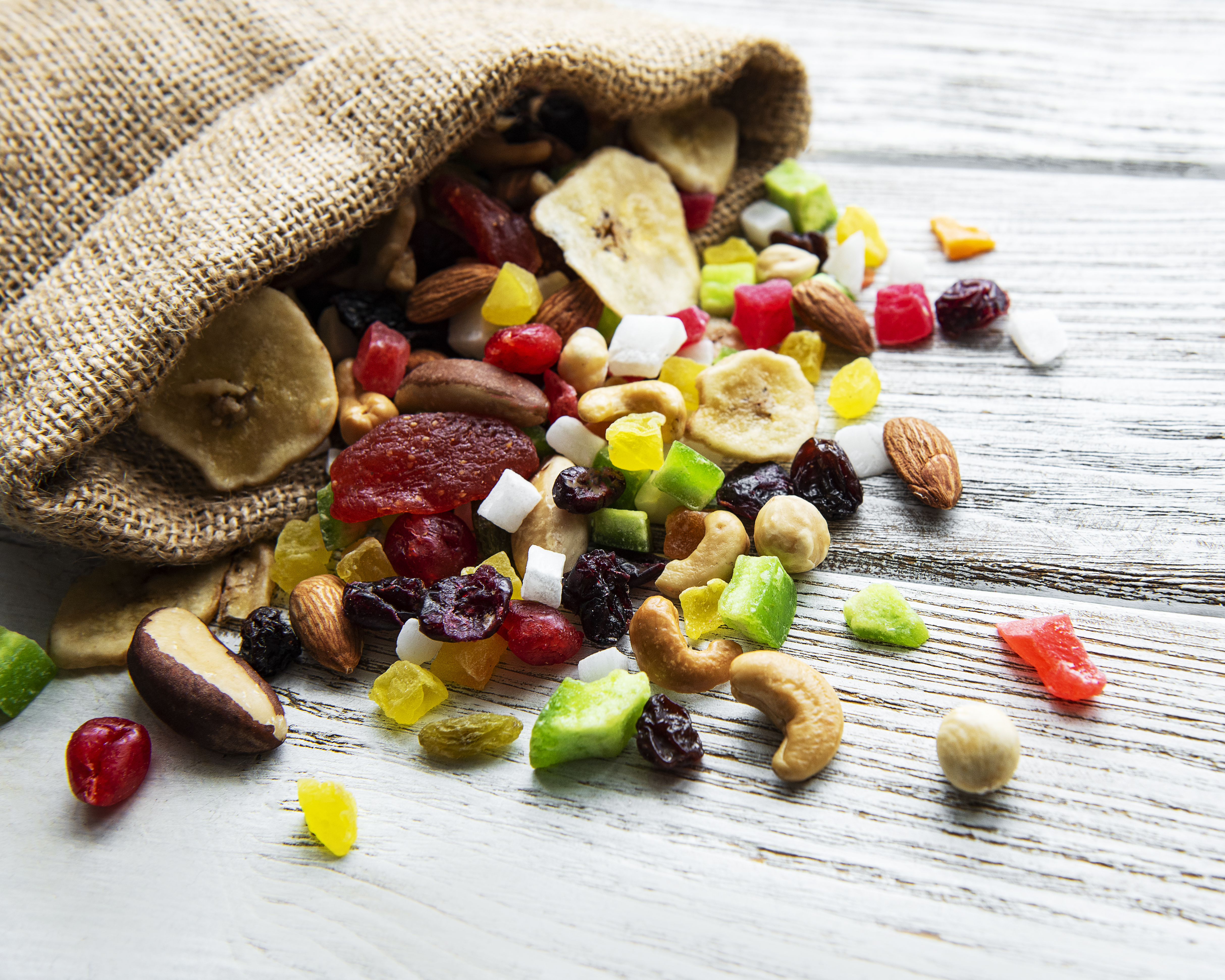 Various dried fruits and mix nuts on a white wooden background.